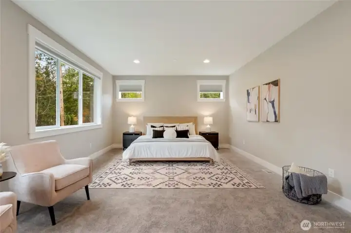 Spacious primary suite with large windows capturing the natural landscape and inviting morning light.
