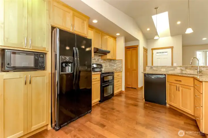 Kitchen with abundance of maple cabinets. Black appliances, tile, and granite countertops