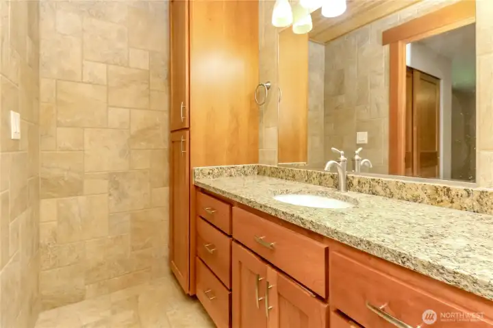 Fully tiled bathroom with maple cabinets and granite