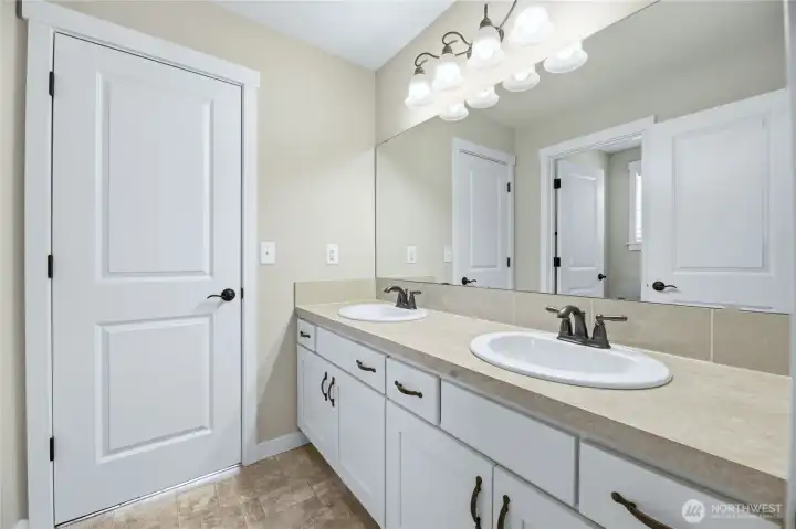 Dual-entry bathroom features a double-sink vanity layout with a separate, private door enclosing the tub/shower and water closet.