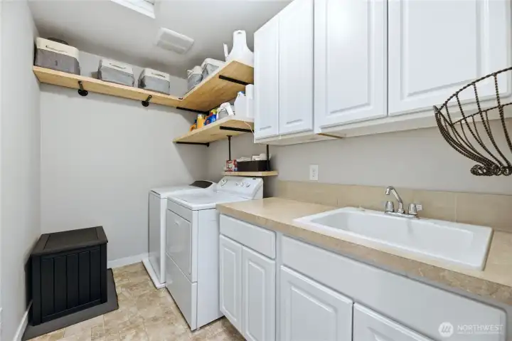 Convenient upstairs laundry room features a built-in utility sink, upper/lower cabinets, and beautiful beechwood shelving for extra storage.