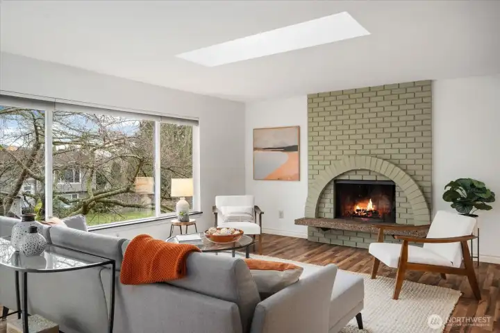 Beautiful living room featuring expansive picture window, skylight, and cozy wood-burning fireplace. Check out the gorgeous flooring throughout the main floor!