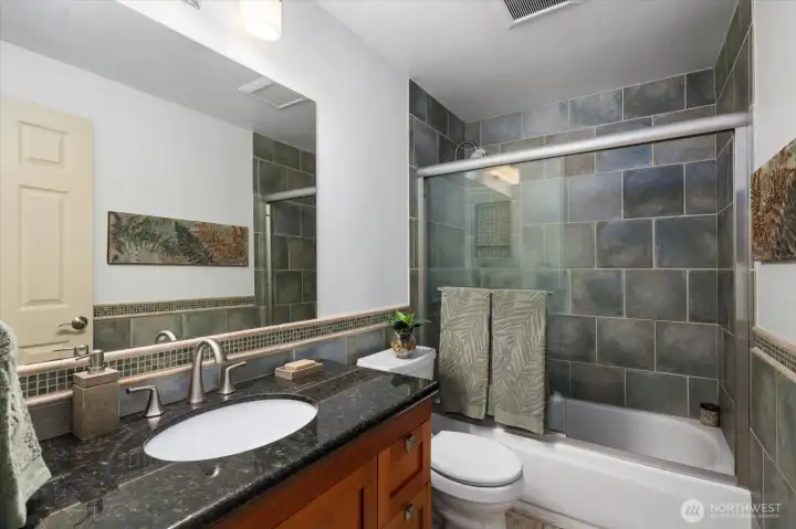 Beautiful hallway bathroom with a large vanity, gorgeous tiling and detailing throughout!