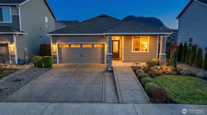 Stunning twilight view of this beautifully upgraded rambler showcasing over $30K in thoughtful improvements, lush landscaping, and inviting curb appeal.