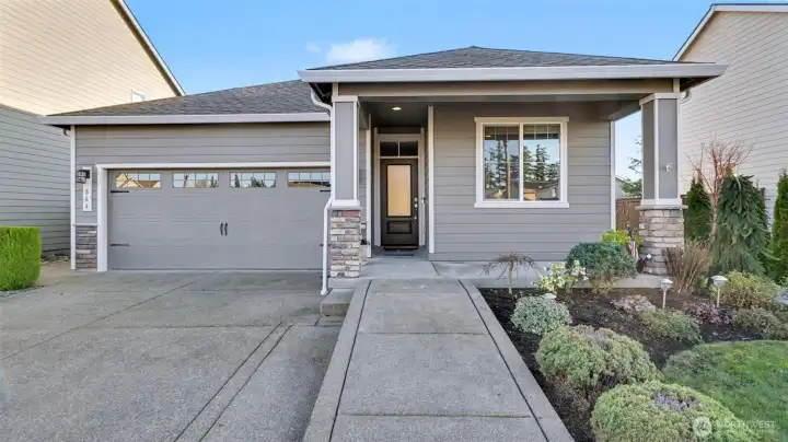 Bright daytime view highlighting the wheelchair-accessible concrete front entrance and wide, welcoming approach to the home.