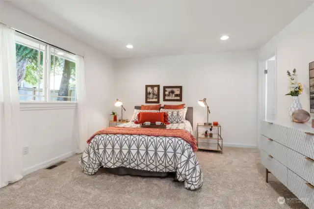 Considerable primary suite with back yard views and plush new carpeting, offers space for king- or queen-sized bed and dresser