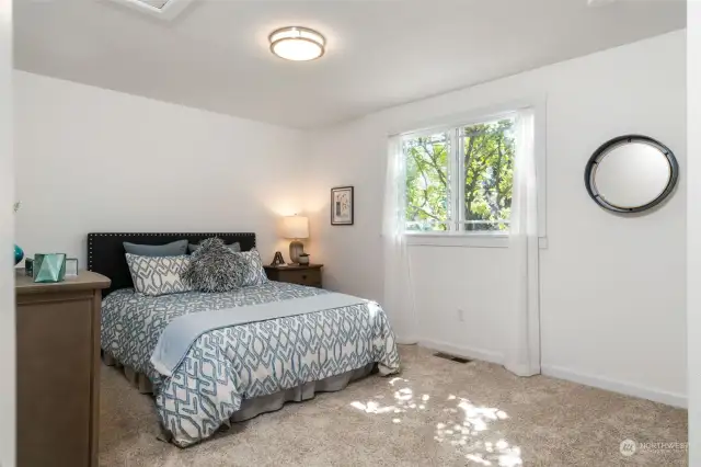 Generous secondary bedroom with front yard views, accommodates a queen-sized bed and dresser