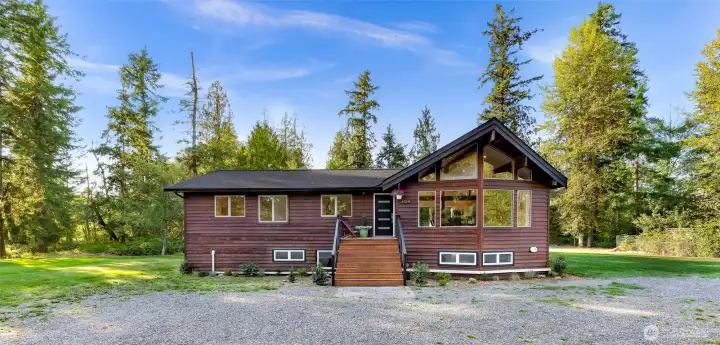 A circular driveway brings you into the home surrounded a level grass field and then trees on all sides.  Lots of graveled parking including space for an RV.