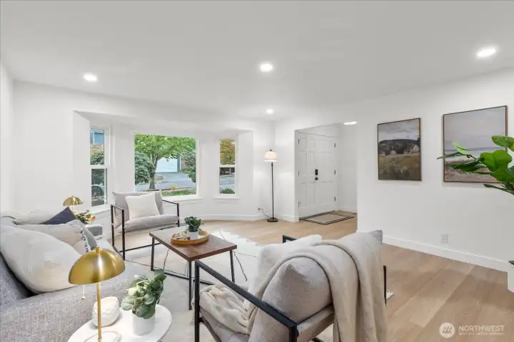 Enter through double doors to the main living area, featuring a bay window, luxury vinyl plank flooring, fresh paint, craftsman trim, and adjustable canless lighting.