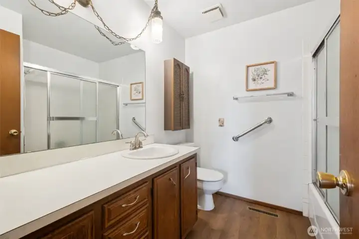 Hall bath with large vanity, vintage light, shower/tub combo. New flooring and mirror.