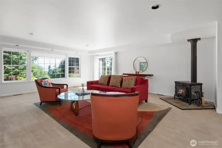 Spacious living room with huge view windows, sliding glass door to front patio and wood burning stove.