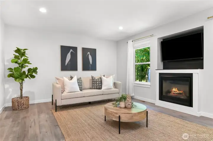 Spacious living room with a cozy gas fireplace and large picture windows looking out to the lush backyard. Spacious living room with a cozy gas fireplace and large picture windows looking out to the lush backyard.