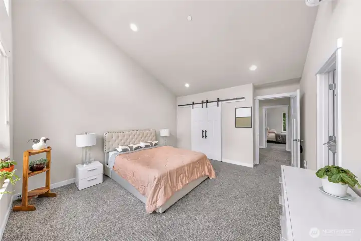 Primary bedroom with barn door to walk in closet. Door on far right wall is to the en suite bathroom Primary bedroom with barn door to walk in closet. Door on far right wall is to the en suite bathroom