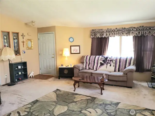 Another Picture of the Enormous Living Room with an Economical Free Standing Gas Stove to Heat the Whole Home From the Dining Room Area Looking at the Front Entry Door.