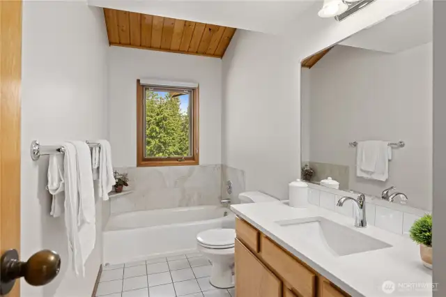 Shared bath on main level with new tile surround on bath and new quartz countertops.