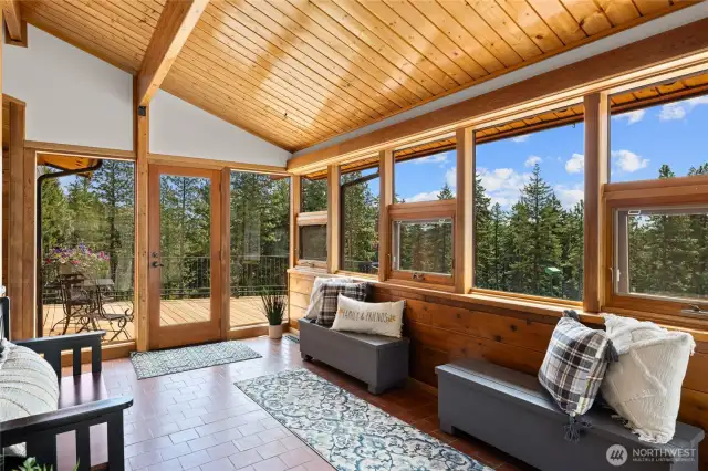 The entry features a light-filled, sunroom-style vibe with beautiful views of the property.