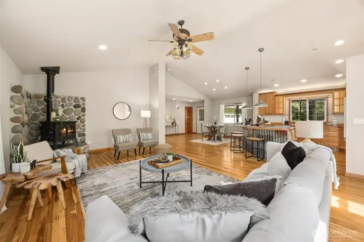 Open floor living space with corner fireplace, ceiling fan.