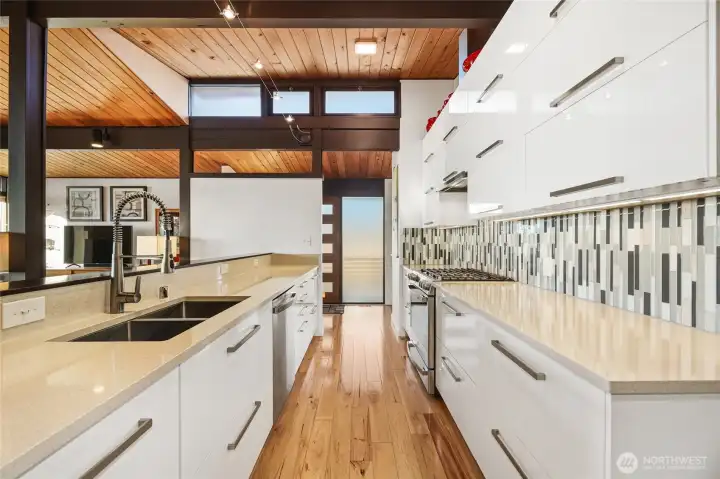 Sleek chef’s kitchen with quartz countertops under beautiful clearstory windows...