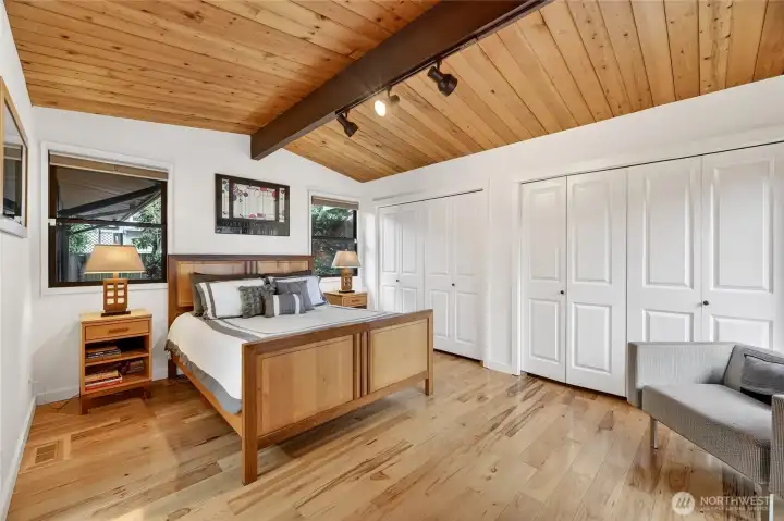 Primary bedroom with wall of closets under vaulted cedar.