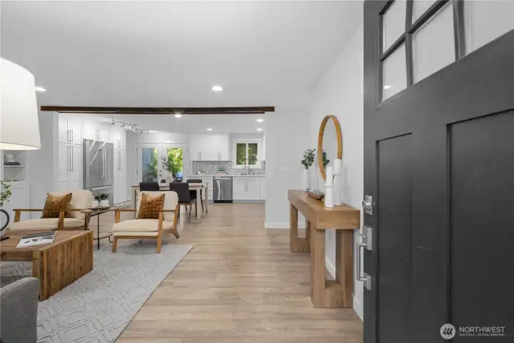 The entry opens into a bright, refreshed interior where light colors, modern finishes, and an easy open flow make the home feel calm and inviting. Freshly painted walls carry the same soft color throughout, giving each space a clean, cohesive feel, while the new luxury laminate hardwood continues from room to room for a beautifully unified look.