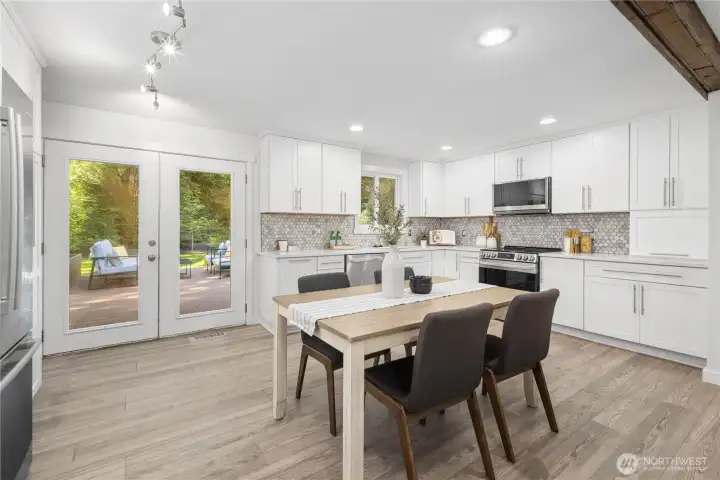 The large dining area helps blend the kitchen and living spaces together, keeping the open-concept layout feeling connected and easy. Glass-paneled French doors open to the backyard deck, bringing in natural light and garden views.