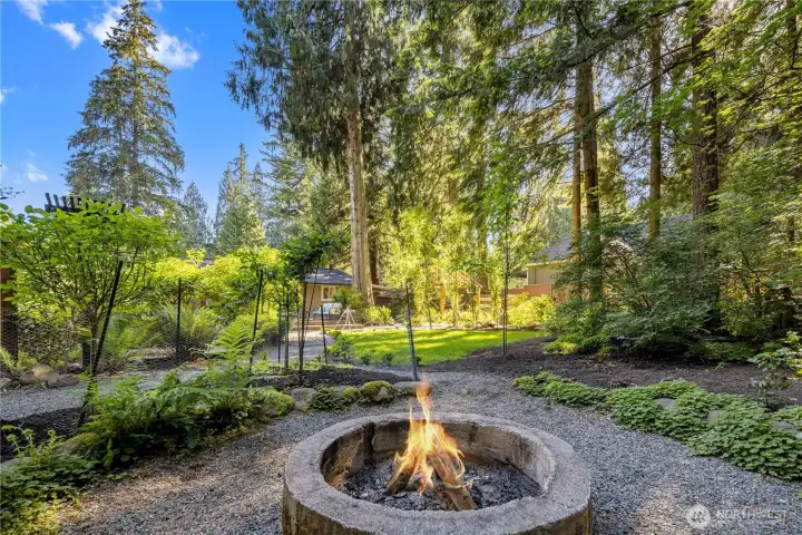 There’s something special about gathering around a campfire in the woods, and here, that feeling is right in your own backyard! The cement fire pit area creates a memorable outdoor destination, surrounded by ferns,  evergreens, and the peaceful privacy of the natural setting.