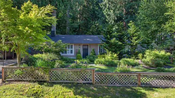 A lattice fence lines the front yard, framing a lovely garden filled with plants that bloom at different times of year, including peonies and honeysuckle, for lasting beauty and interest. The front lawn adds a soft finishing touch, with space for kids and pets to play while enhancing the home’s picturesque curb appeal.