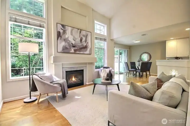 Natural light pours through expansive windows, highlighting the open-concept design and warm hardwood floors. Natural light pours through expansive windows, highlighting the open-concept design and warm hardwood floors.