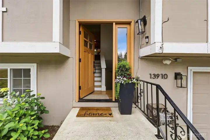 A warm and inviting entryway featuring a solid wood craftsman door with sidelight, black hardware, and fresh seasonal plantings. A warm and inviting entryway featuring a solid wood craftsman door with sidelight, black hardware, and fresh seasonal plantings.