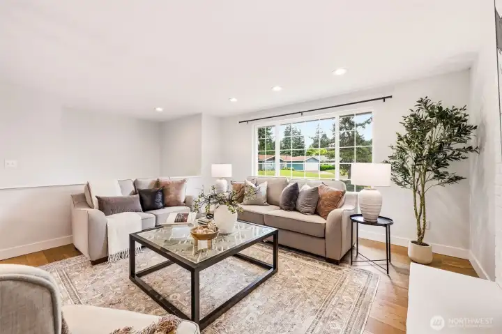 A spacious and light-filled living area with large picture windows, hardwood floors, and an open feel perfect for entertaining. A spacious and light-filled living area with large picture windows, hardwood floors, and an open feel perfect for entertaining.
