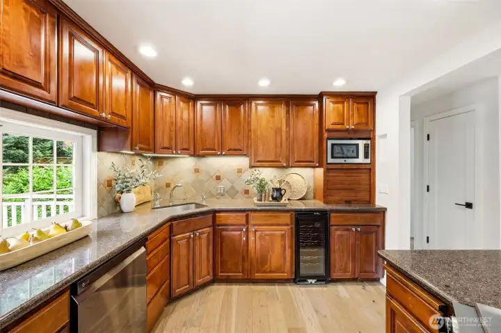 bundant custom cabinetry, a tile backsplash, built-in wine cooler, and granite counters make this kitchen as functional as it is beautiful. bundant custom cabinetry, a tile backsplash, built-in wine cooler, and granite counters make this kitchen as functional as it is beautiful.