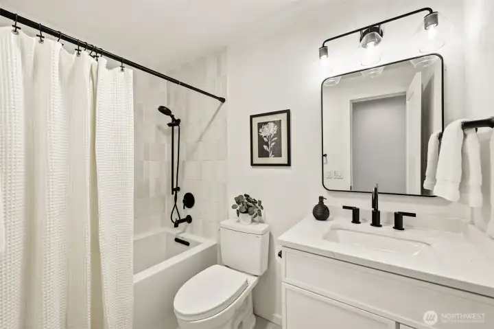 A freshly updated full bathroom with crisp white finishes, black fixtures, and a tub-shower combo — clean, modern, and move-in ready. A freshly updated full bathroom with crisp white finishes, black fixtures, and a tub-shower combo — clean, modern, and move-in ready.
