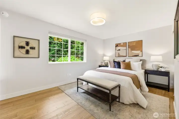 A generous primary bedroom with hardwood floors, large windows framing the treetop greenery, and a tranquil, retreat-like atmosphere. A generous primary bedroom with hardwood floors, large windows framing the treetop greenery, and a tranquil, retreat-like atmosphere.