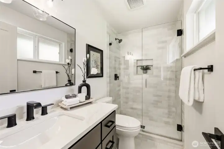 The stunning en suite bathroom features a glass-enclosed tile shower, quartz counters, black hardware, and high-end finishes throughout. The stunning en suite bathroom features a glass-enclosed tile shower, quartz counters, black hardware, and high-end finishes throughout.