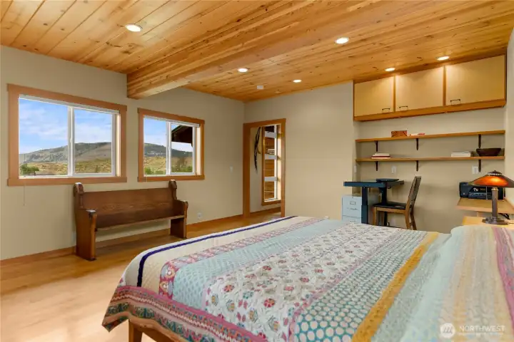 Spacious main-floor bedroom with abundant natural light, small office area.
