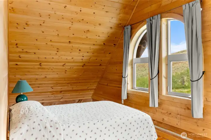 Upper guest bedroom with charming arched windows & mountain views.