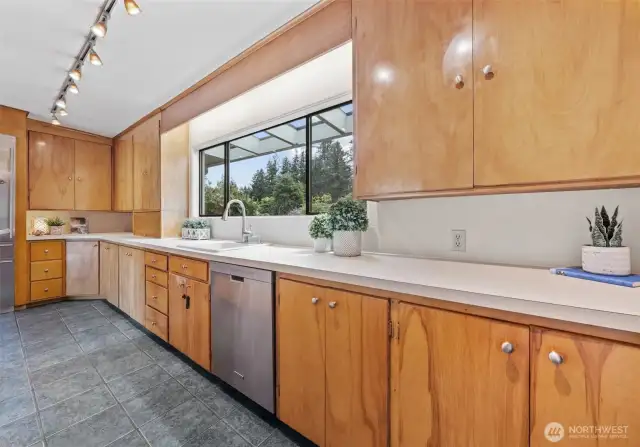 A big kitchen window highlights the gorgeous flowering trees and plants.