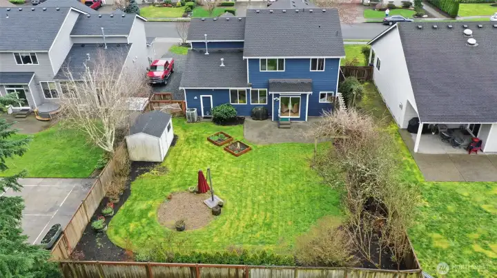 Aerial view of your new backyard oasis! Fully fenced, wonderful paved patio, garden beds, trellis, fire pit space, and a storage shed!