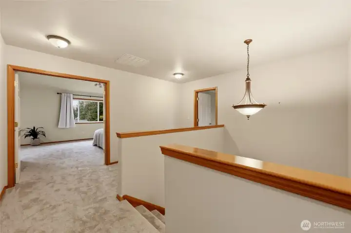 A well sized landing at the top of the stairs. Behind are the first and second bedrooms as well as the full bathroom. The door on the right leads to the bonus room, while through the french doors we enter the primary suite.