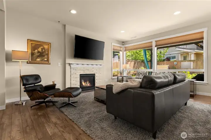 Spacious great room bathed in natural light, with cozy gas fireplace and beautiful wood-look laminate floors that create an inviting atmosphere