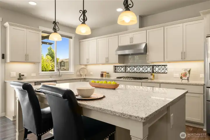 Pendant lights above the eating bar offer ambiance, and transom windows brighten the kitchen, creating a sunny spot for meal prep and morning coffee