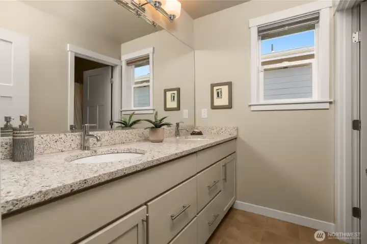 Upstairs main full bath is conveniently located between two secondary bedrooms, with considerate separation between vanities and toilet & shower area
