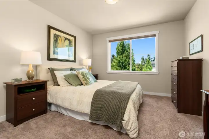 Secondary bedroom with walk-in closet and large window offers ample space for a queen-sized bed and dresser