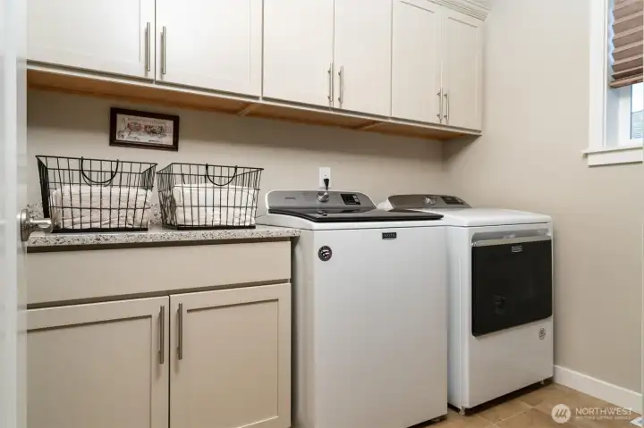 Thoughtfully positioned upstairs laundry room with built-in cabinets and walk-in closet, ideal for storing home supplies and cleaning products