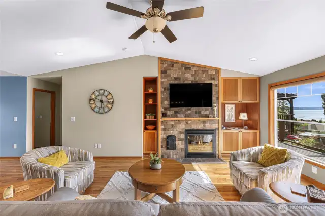 Another view of the living area showcases cozy, coordinated textures and inviting seating around the warm fireplace—ideal for quiet mornings or evening entertaining. Built-in cabinetry adds charm and practical storage.