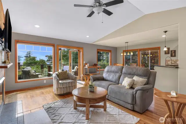 Enjoy indoor-outdoor living from the heart of the home—French doors open to a spacious deck framed by trees and filtered views of the water. Thoughtfully arranged furniture encourages gathering in this sunlit retreat.