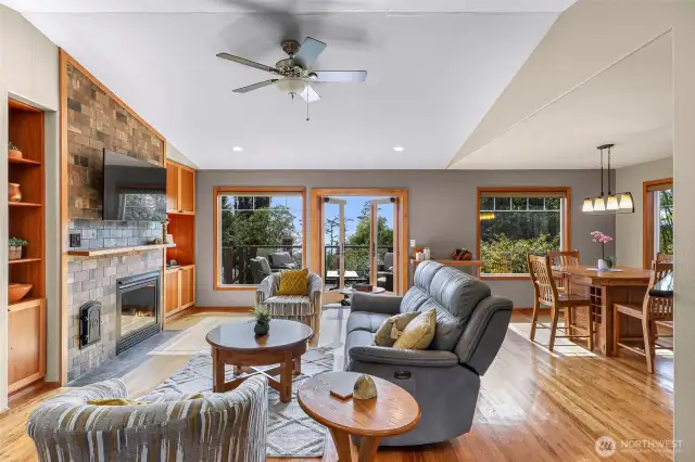 The open-concept living area invites relaxation with its vaulted ceilings, custom stone fireplace, and panoramic views of Birch Bay through oversized windows and French doors. Natural light floods the space, enhancing the warm wood accents and seamless flow to the expansive deck.