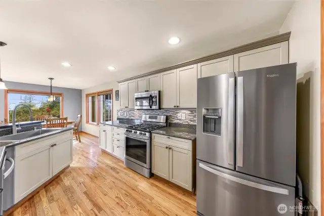 Blending style and function, this wide-angle shot reveals how the kitchen connects to a cozy dining nook and outdoor views, with every surface finished in quality materials and thoughtful lighting.