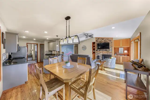This wide-angle view captures the open-concept living, dining, and kitchen areas—where hardwood flooring, warm tones, and vaulted ceilings make for easy entertaining and daily living.
