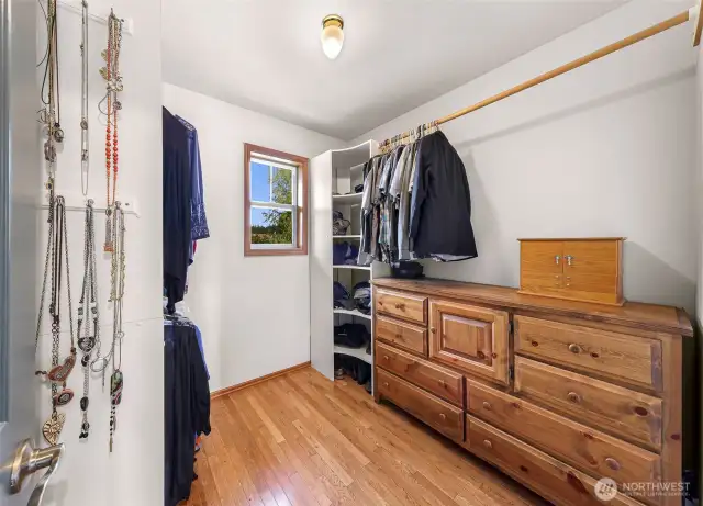 This spacious walk-in closet features built-in storage, hanging space, and hardwood flooring—perfectly suited to meet everyday organizational needs in the primary suite.